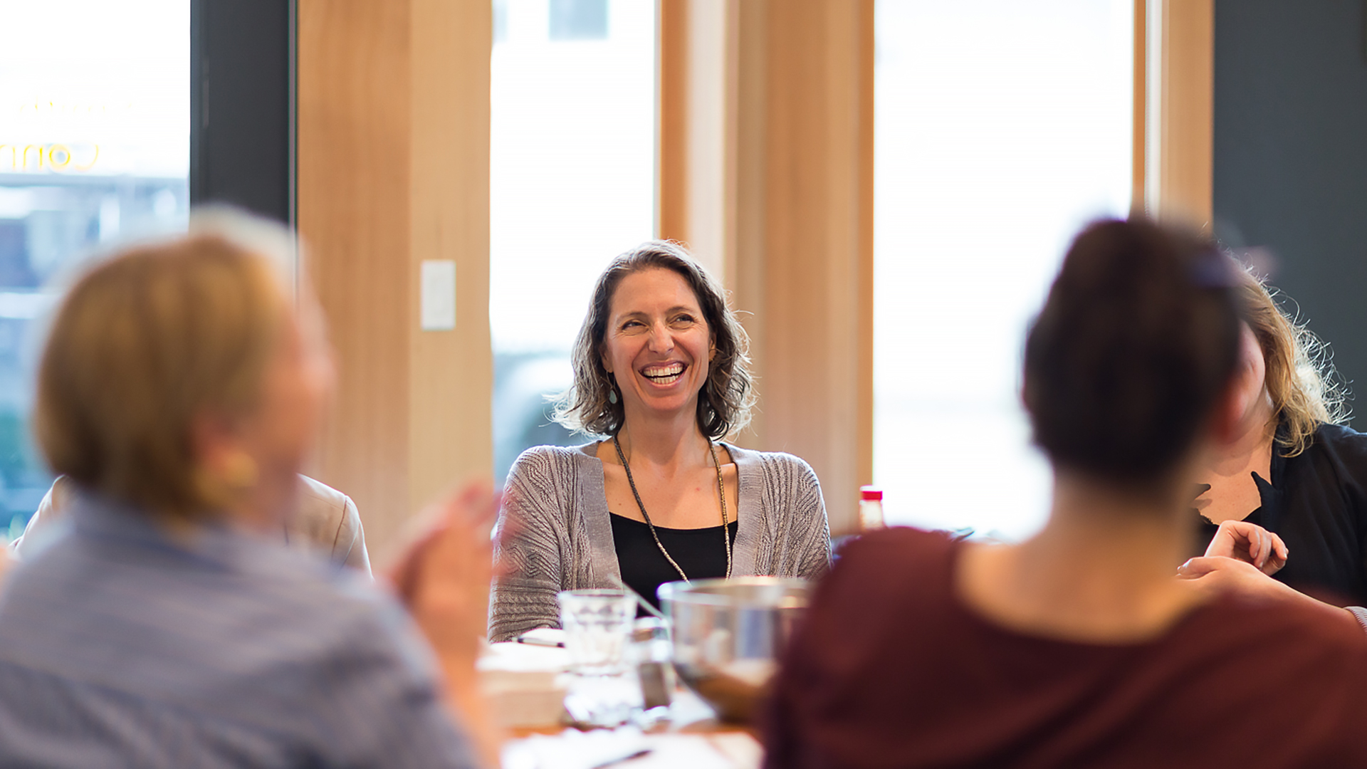Talie Smith smiling at a work session with others around a table.