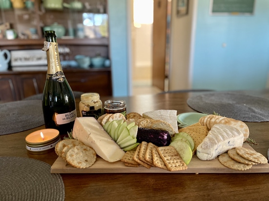 A cheese board with a bottle of champagne and a candle.