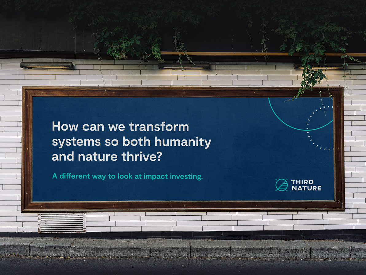 A billboard on a white tiled wall with green vines surrounding that reads "How can we transform systems so both humanity and nature thrive? A different way to look at impact investing. Third Nature"