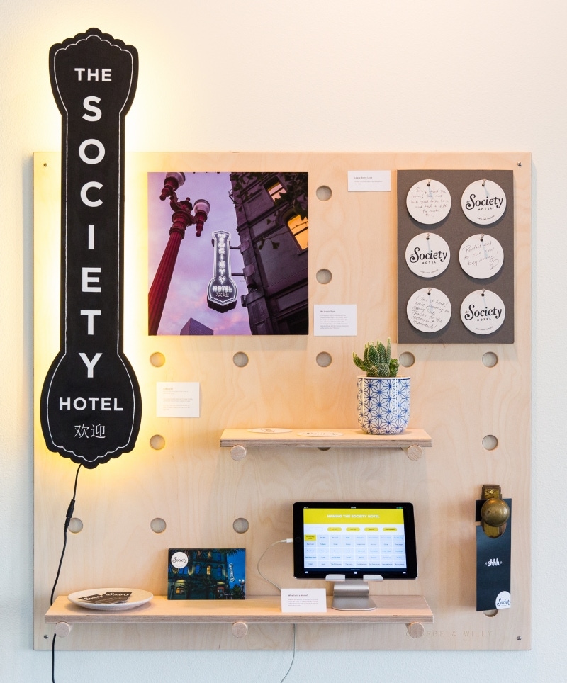 A board covered with The Society Hotel signage and marketing materials.
