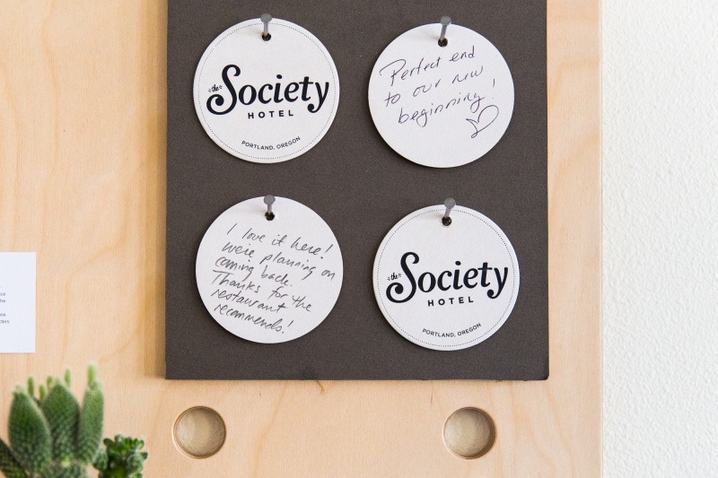 The Society Hotel coasters hanging on a board.