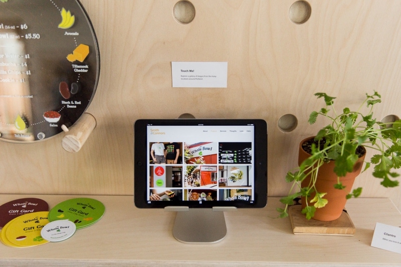 The Whole Bowl website on a laptop surrounded, with menu plate, coasters and cilantro.