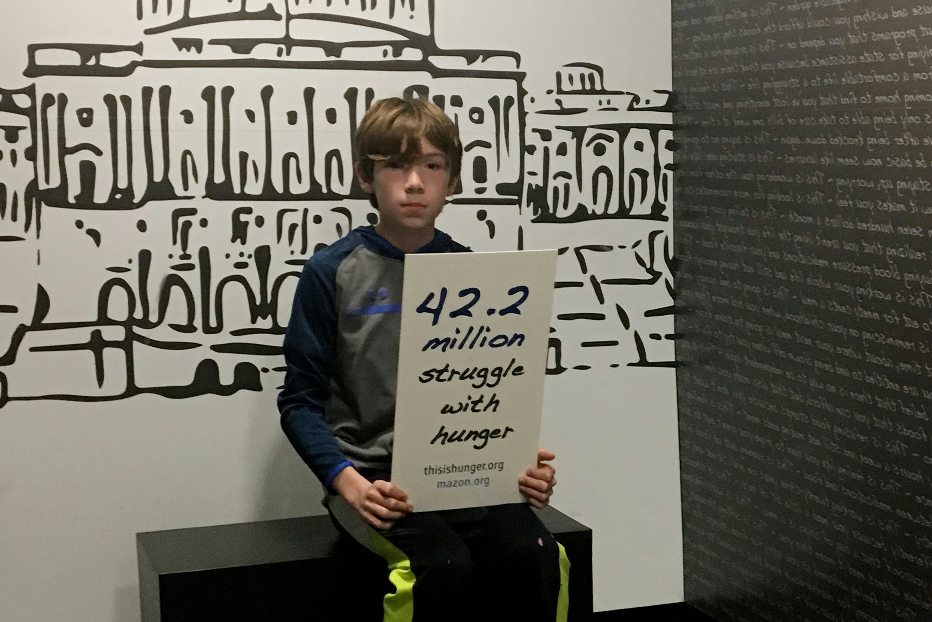Young boy holding sign that says 42.2 million struggle with hunger.