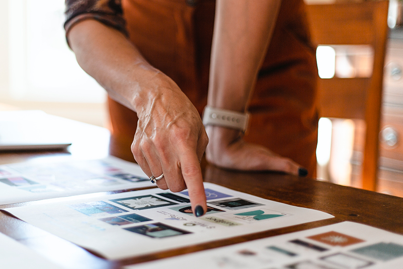 Creative Director pointing to design work laid out on table. 