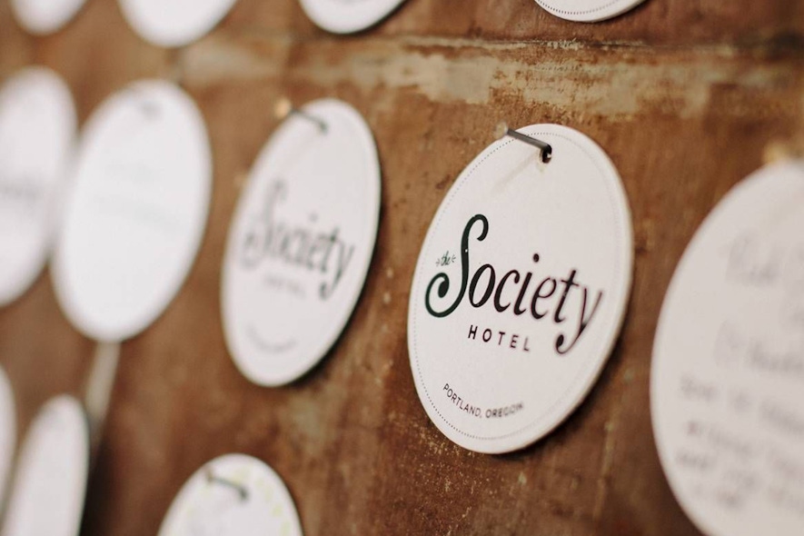 The Society Hotel round placards hanging from nails on a wooden board.