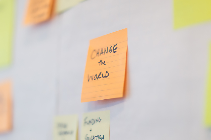 Post it note with the words change the world. 