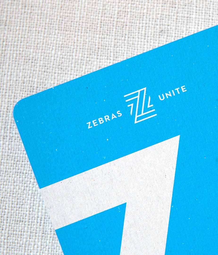 Closeup of the Zebras Unite primary logo on collateral using the brand blue, against a neutral textured background