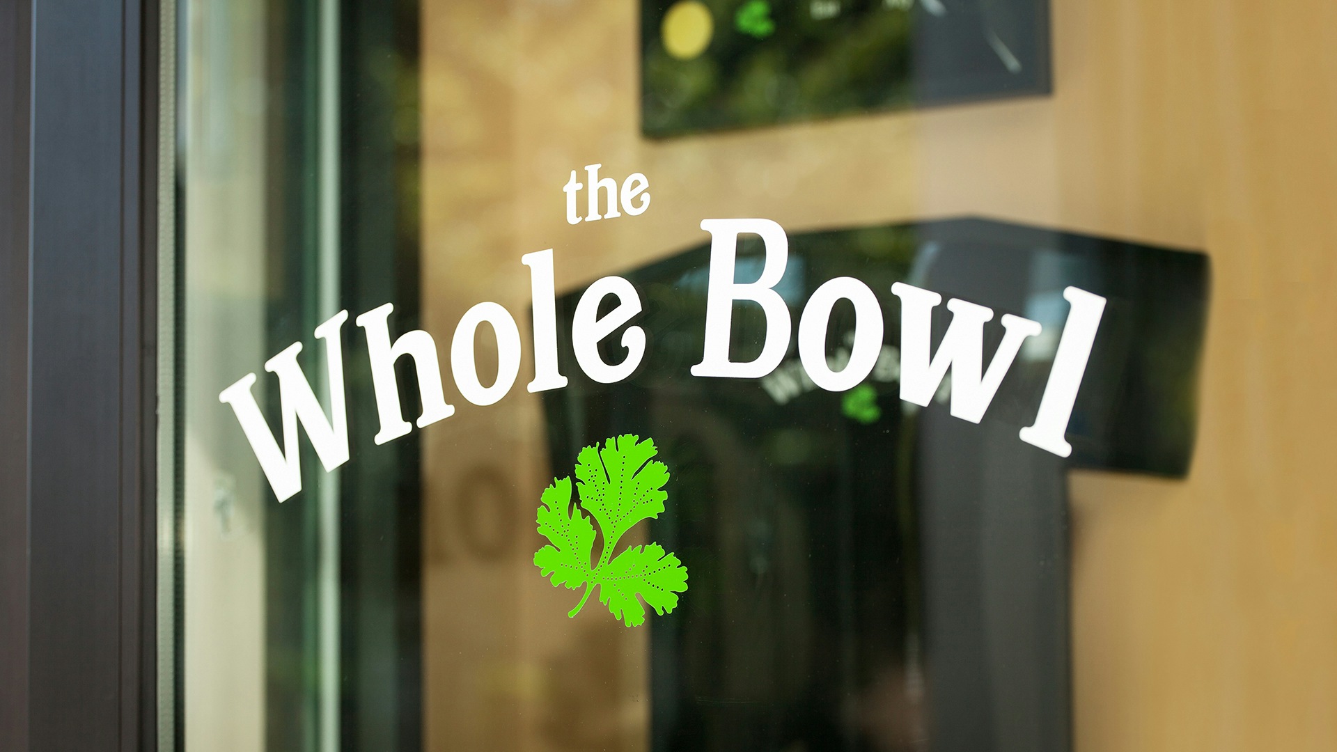The Whole Bowl logo decal on a glass door.