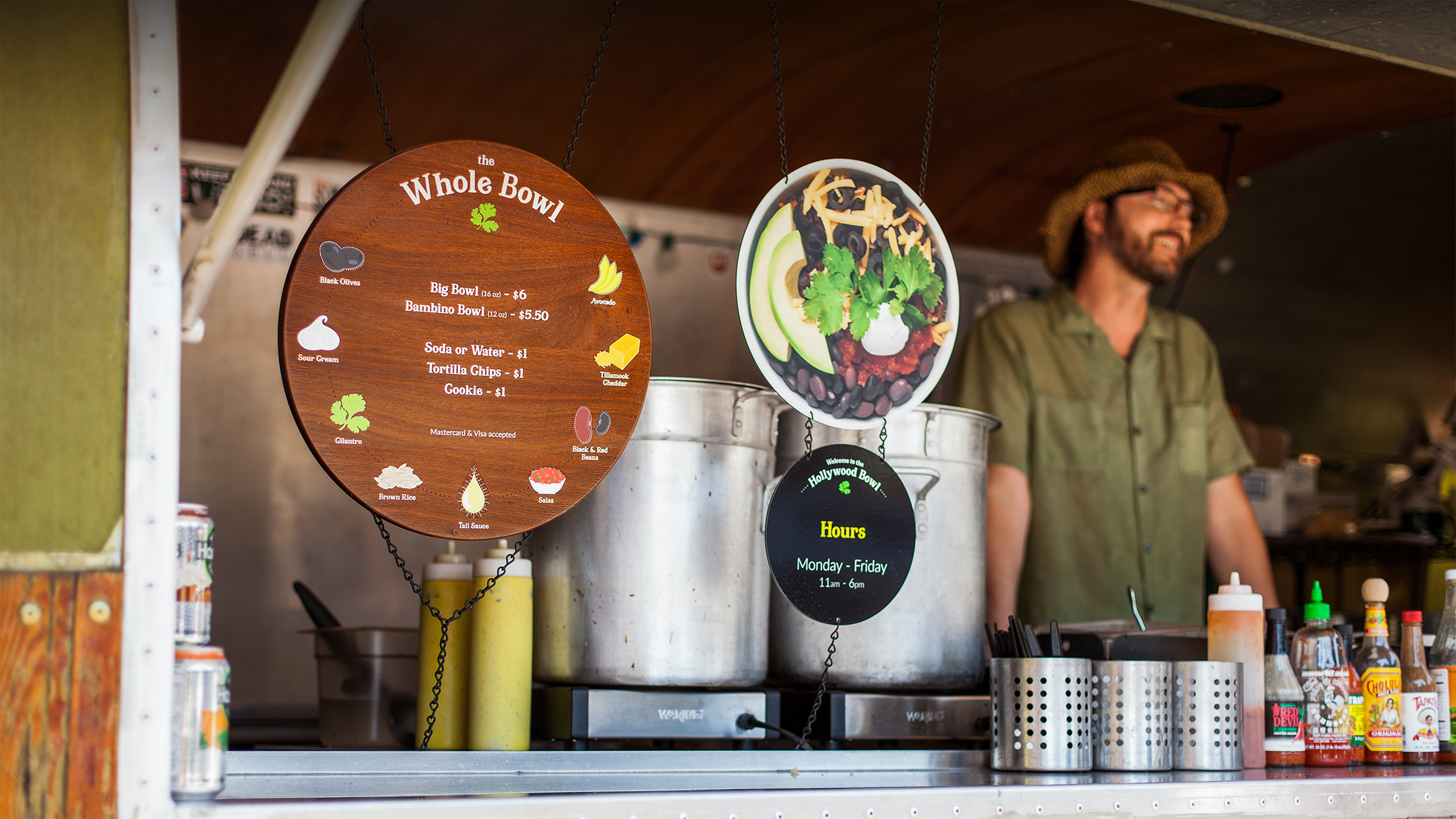 Photograph of a Whole Bowl employee smiling next to the menu.
