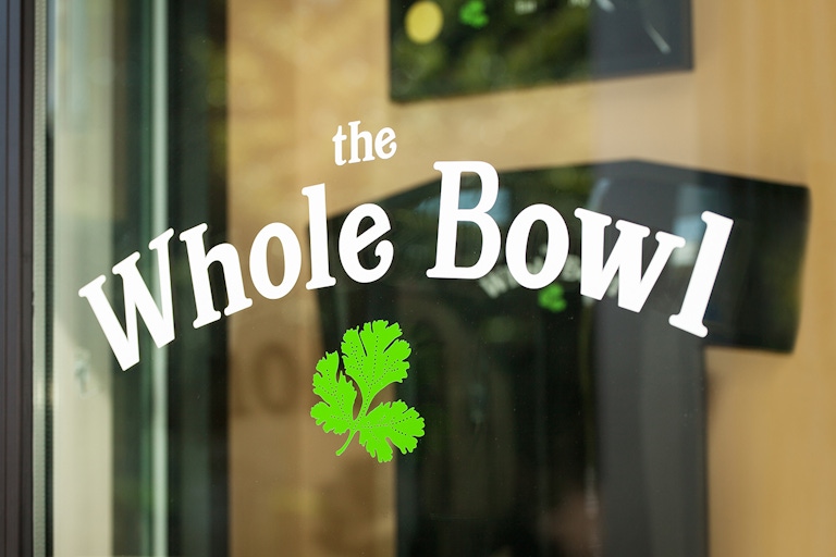 The Whole Bowl logo decal on a glass door.