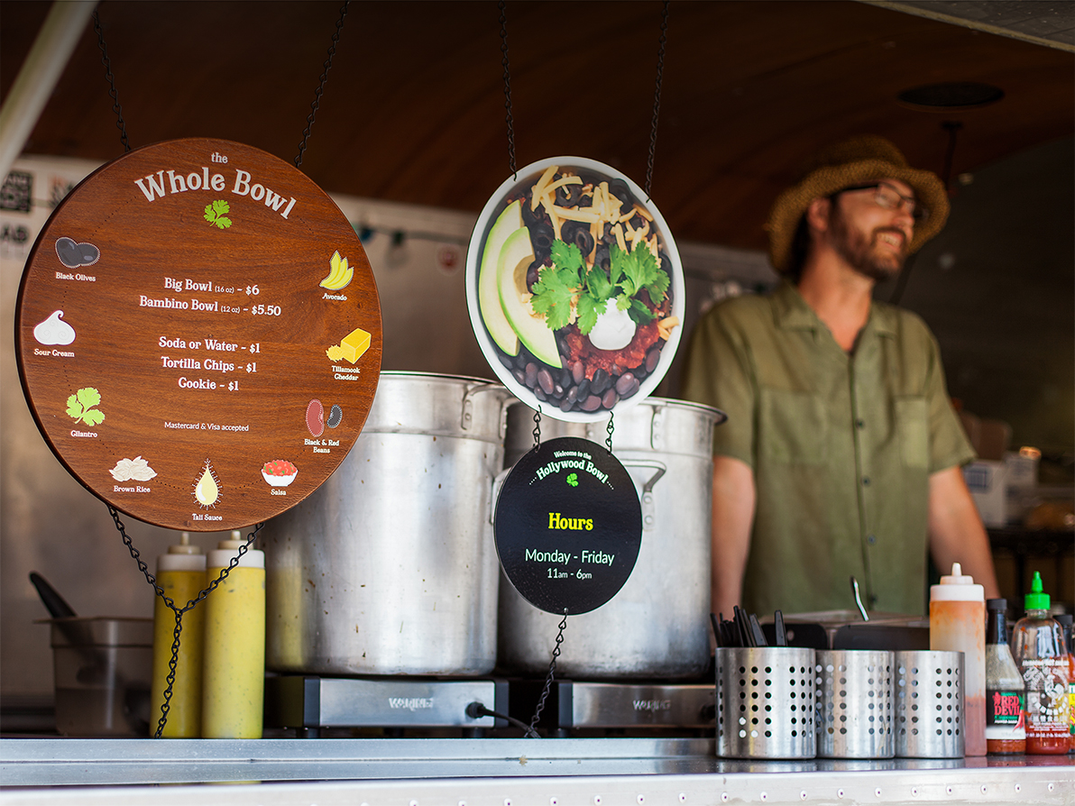 Photograph of a Whole Bowl employee smiling next to the menu.