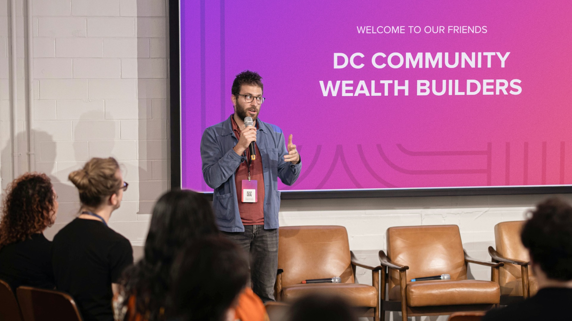 An event speaker standing in front of a design presentation slide matching the event branding.