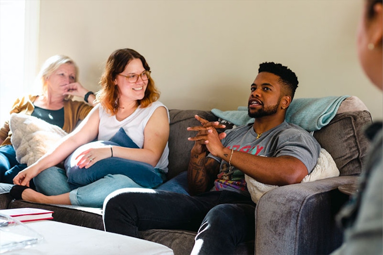 A photograph from a team retreat of team members having a discussion on a couch.