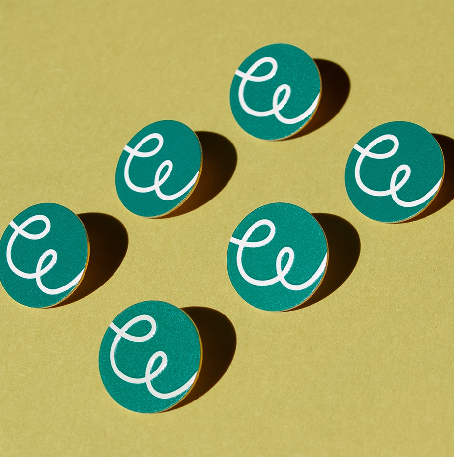 Enamel pins in the design of the new OWT brandmark.